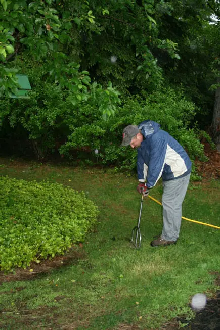 A man is using a hose to water his garden.