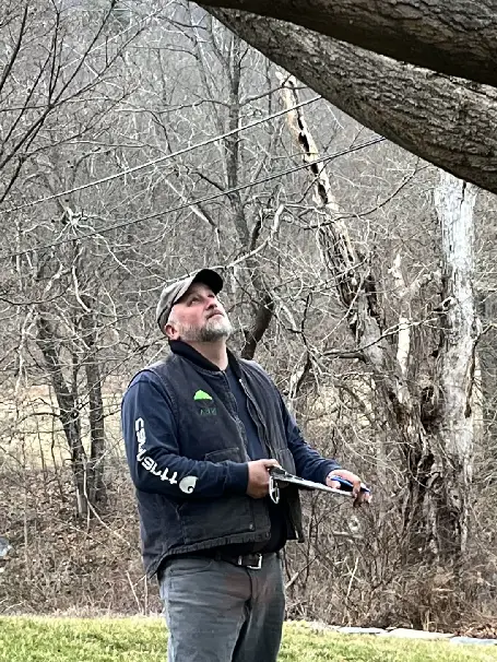 A man holding a frisbee in the woods.