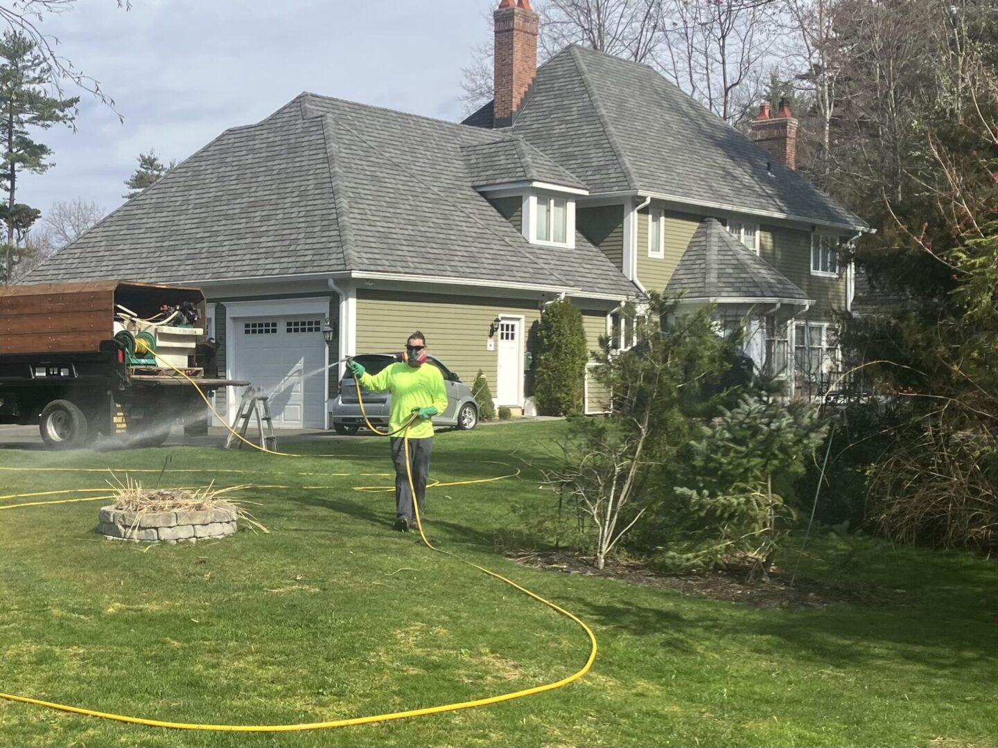 A man standing in the grass with a hose.