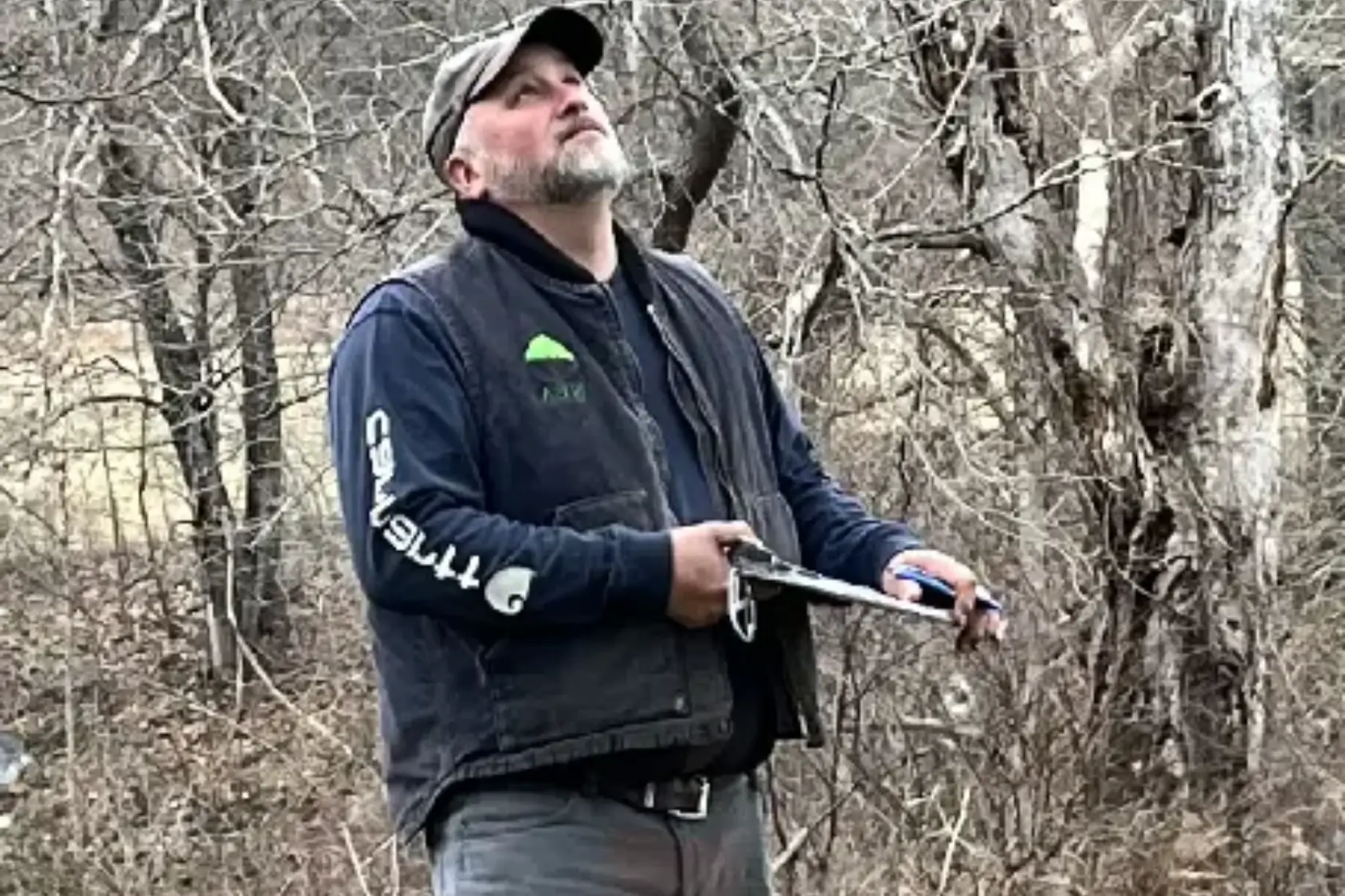 A man holding a frisbee in the woods.